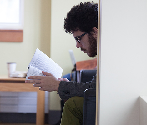 A male student reading a book in the upper-level of study hall